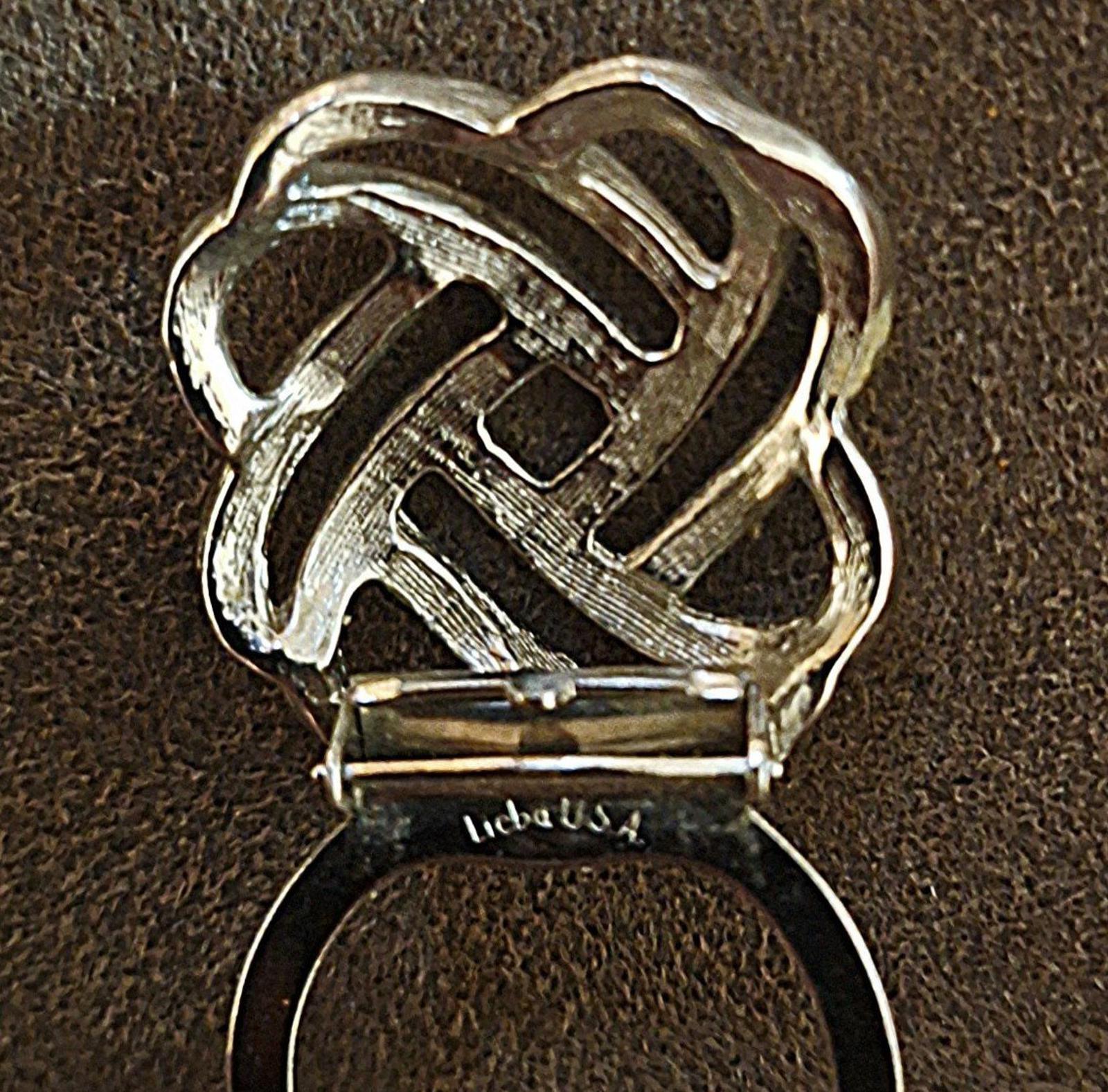 Silver love-knot scarf clip underside with clasp bar and signature mark