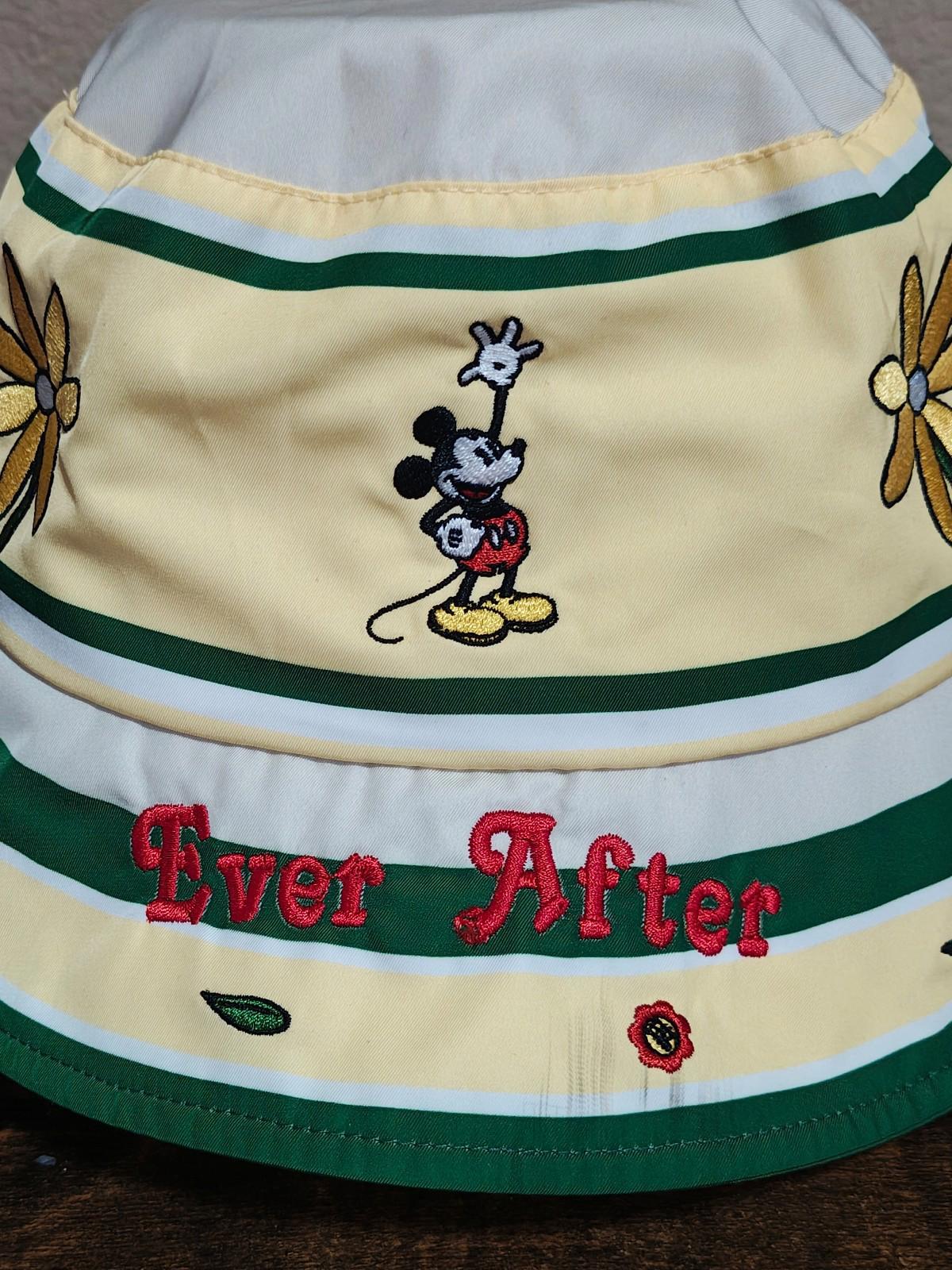 Close-up cream bucket hat with green stripes, Mickey Mouse character and “Ever After” embroidery