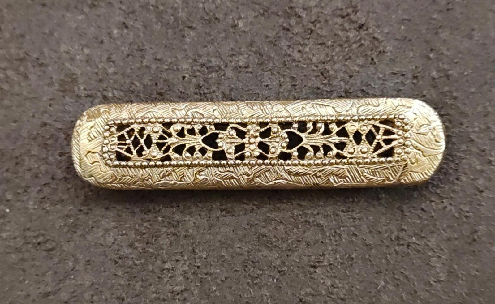 Gold tone Victorian filigree bar brooch with repeating geometric openwork and decorative centerpiece.