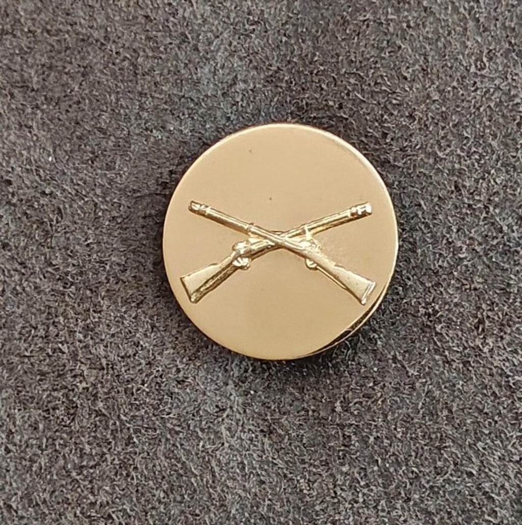 Gold circular brass pin with crossed rifles emblem, front