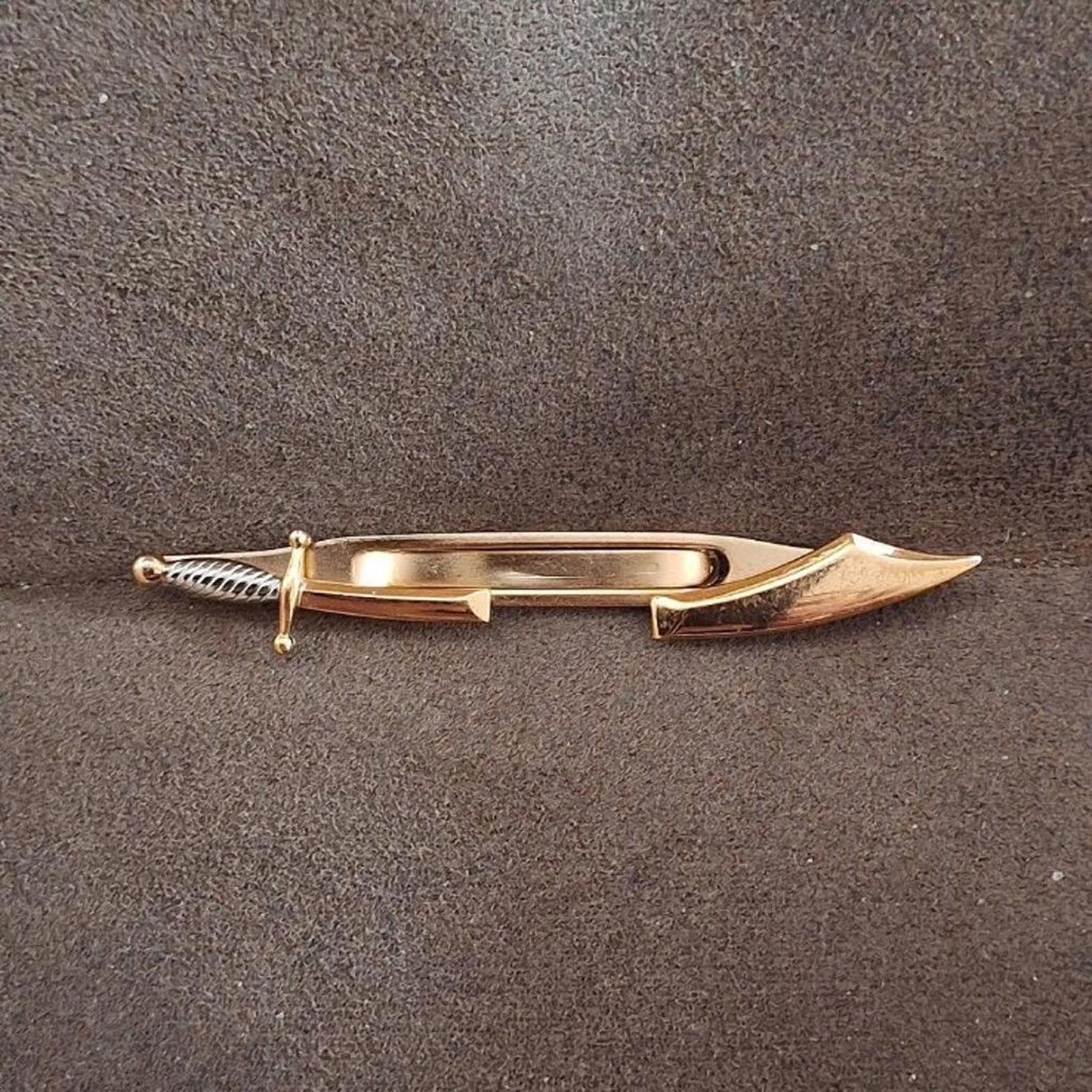 Gold pirate sword tie clip bar angled view, showing pointed blade and ribbed handle