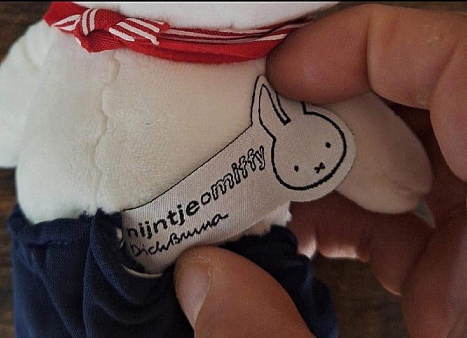 Close-up of white plush fabric with embroidered text and bunny face on navy clothing.