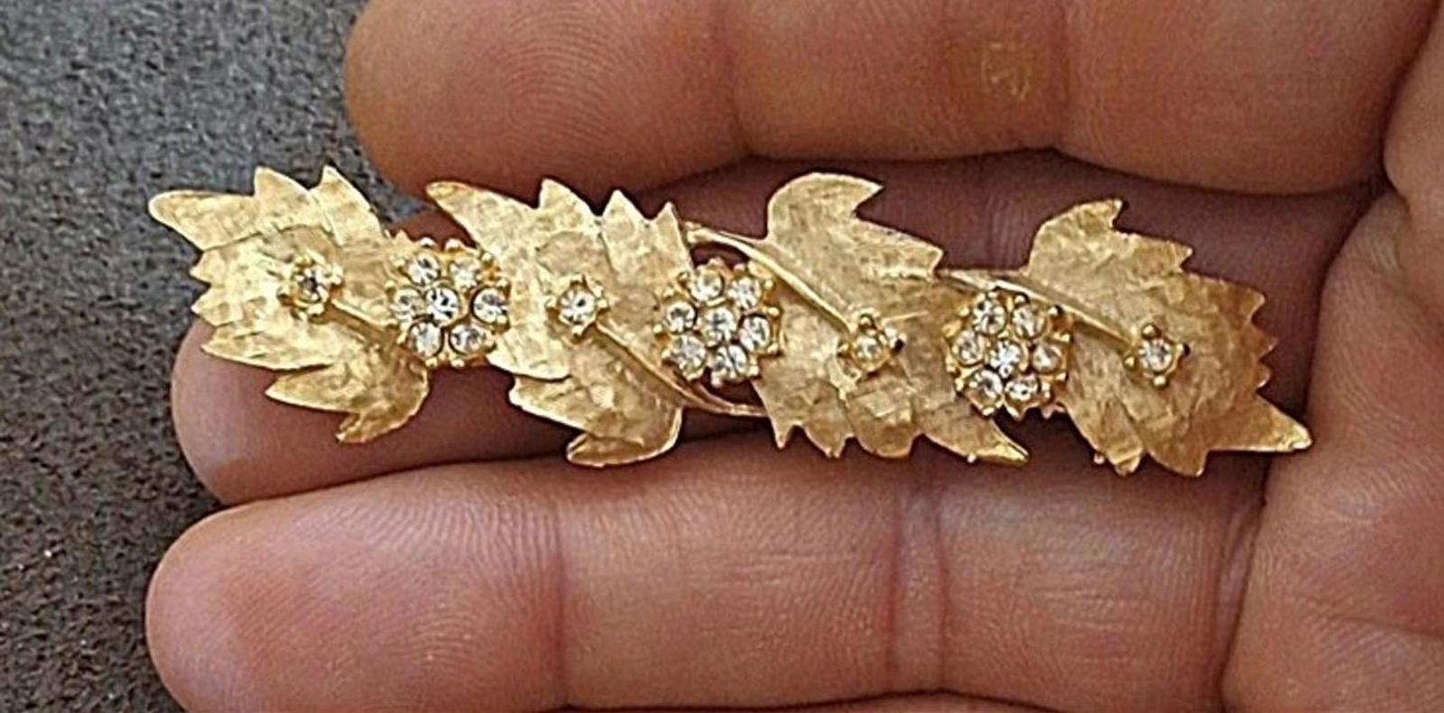 Gold tone leaf rhinestone brooch pin close-up with round crystal clusters
