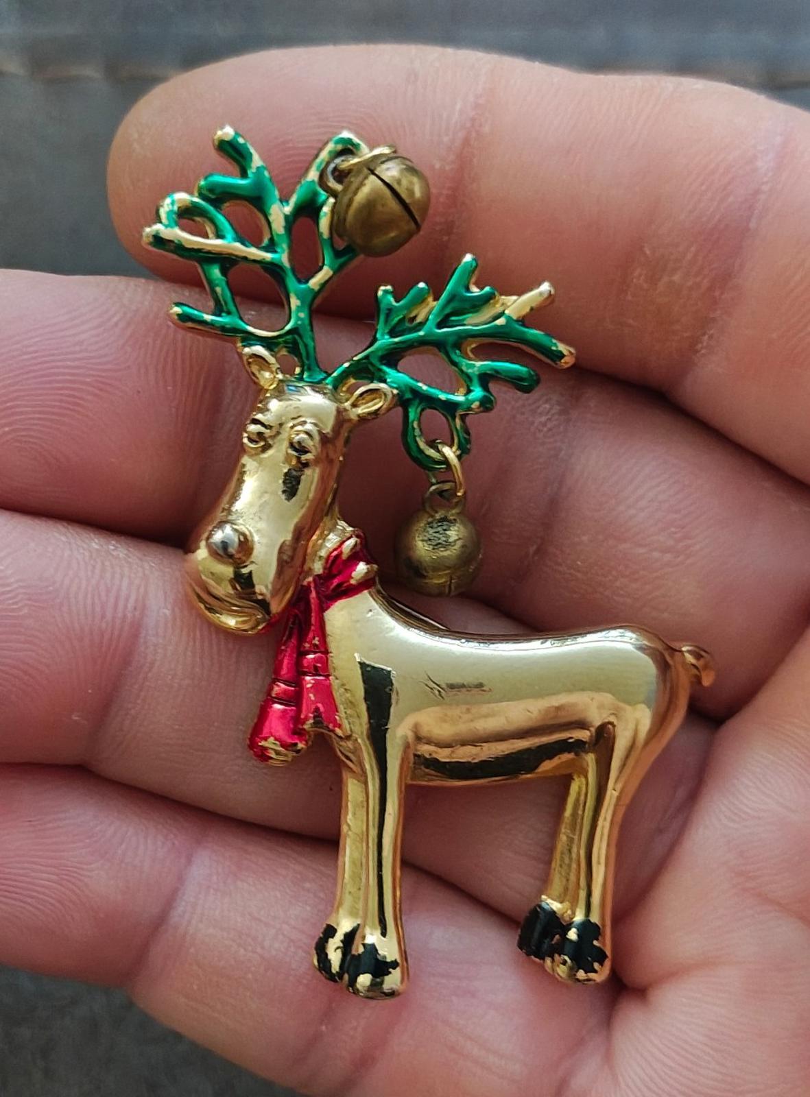 Gold-tone reindeer pin brooch with green antlers, red scarf, and dangling bells.