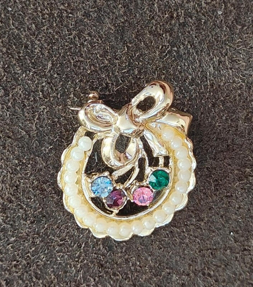 Gold-tone wreath brooch featuring cream faux pearls and blue, green, pink rhinestones.