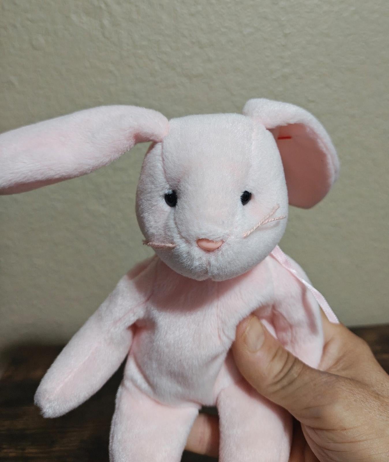 Pink plush bunny face with rosy inner ears and stitched nose, close-up