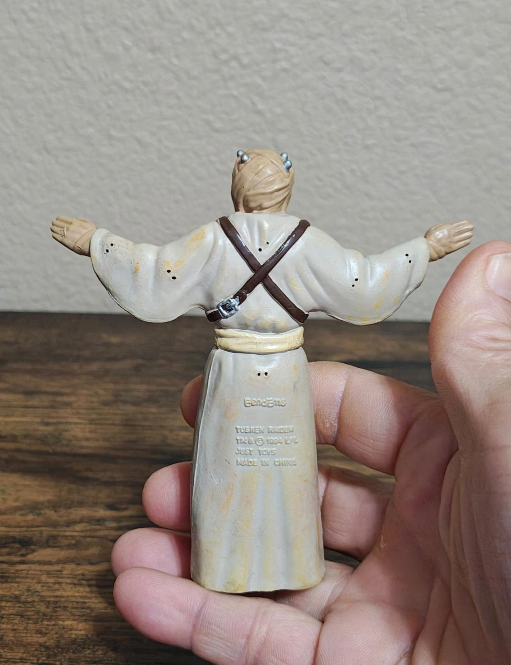 Bendable Tusken Raider action figure in white robe with brown straps, back view, arms out