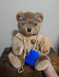 Brown plush teddy bear in tan fringe shirt with beaded headband and chest beads