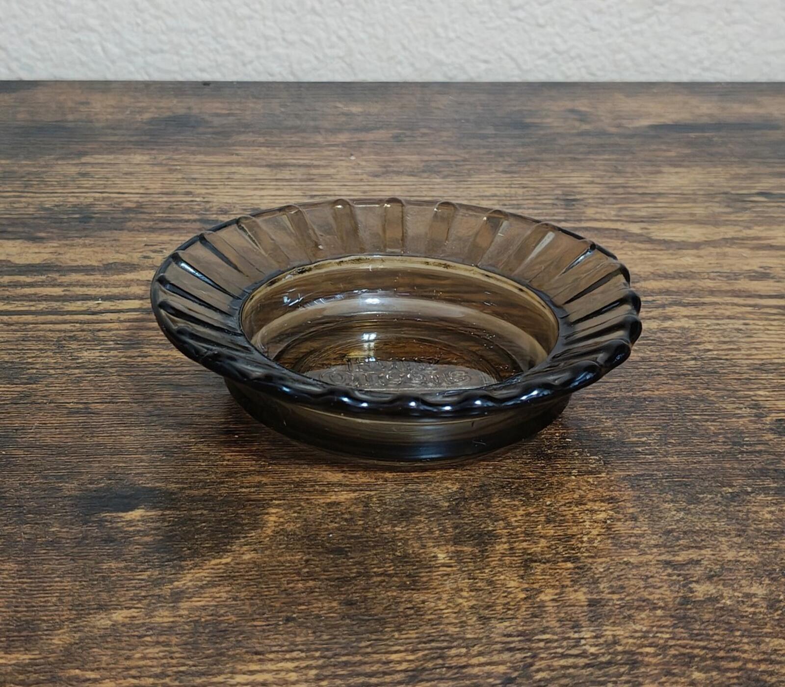 Glass ashtray with ribbed rim and dark-tinted bowl, viewed from above