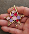 Crown Trifari gold star brooch with red, purple, and pink round enamel cabochons