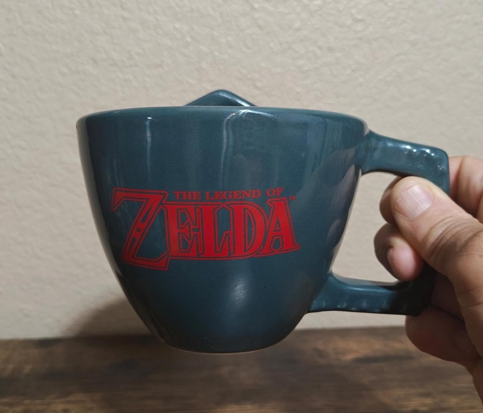 Blue Zelda-themed mug with red 'Legend of Zelda' logo on the cup front.