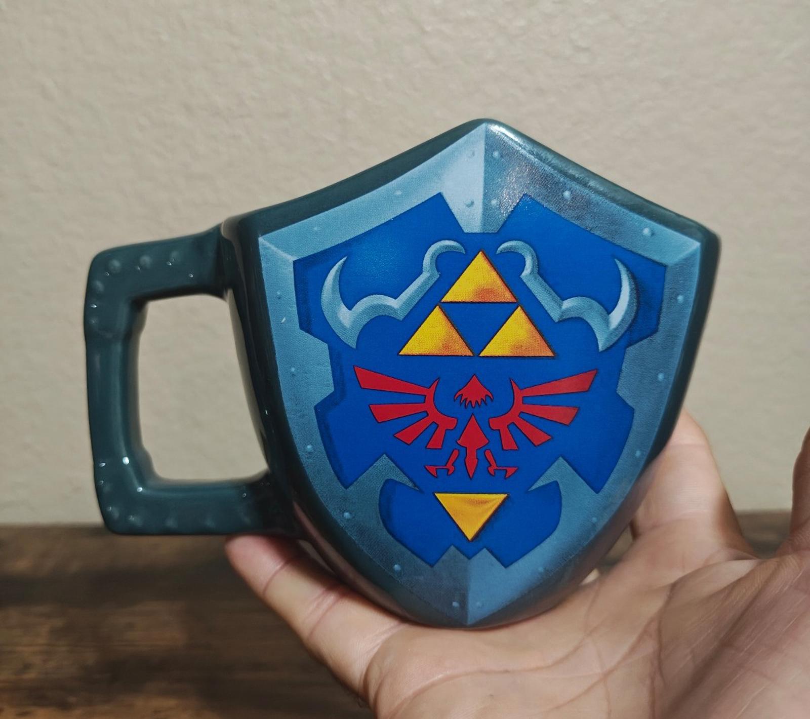 Blue mug with large Hylian Knight-style shield graphic in blue, yellow, and red.