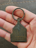 Brass keychain with building charm and circular ring on a hand grip