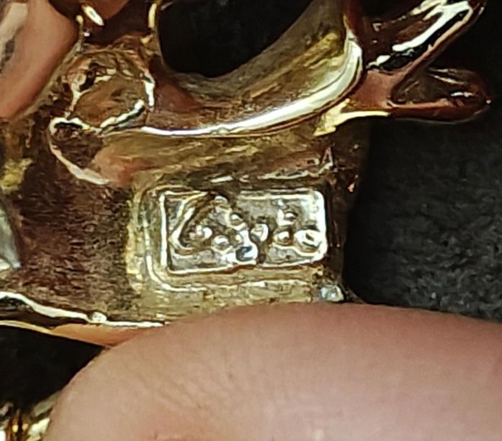 Gold-tone angel brooch pin close-up of engraved signature or hallmarked text