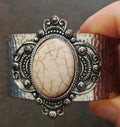 Silver hammered cuff bracelet with oval beige stone and ornate bezel, wide adjustable fit
