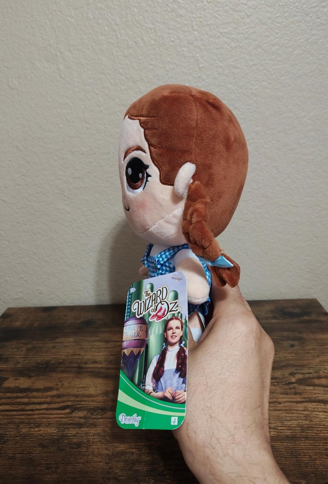 Dorothy-style plush doll side view, blue gingham dress, red shoes, green hangtag