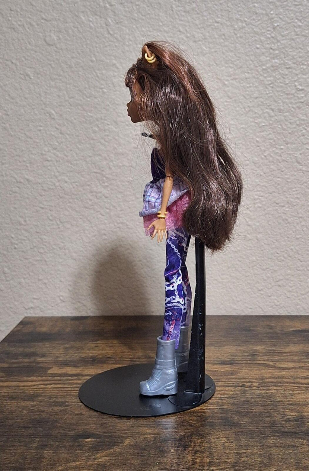 Fashion doll side view showing purple plaid skirt, patterned leggings, and tall boots