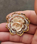 Gold-tone filigree brooch with a round white rose and openwork lace border