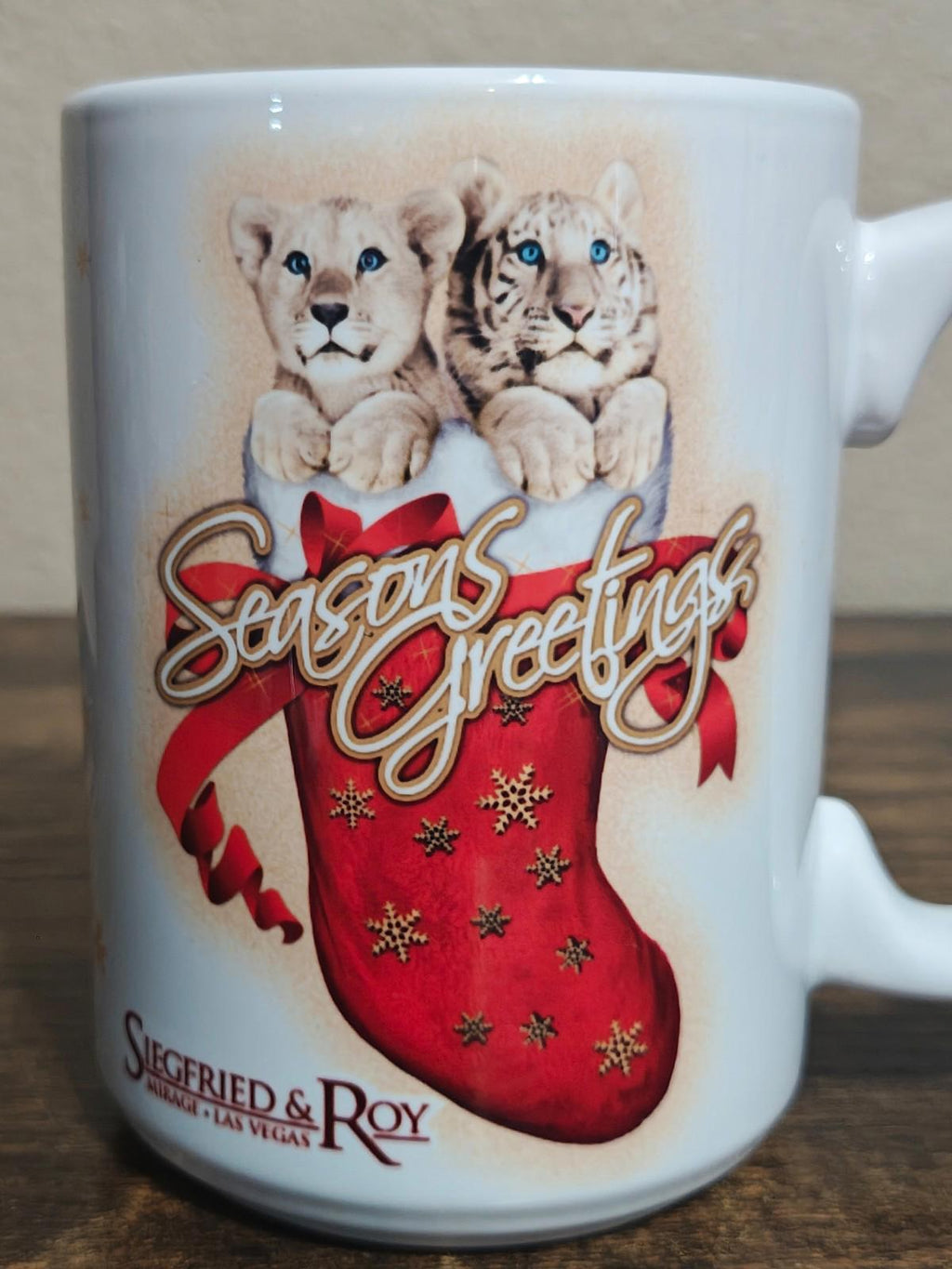White porcelain mug front close-up showing two big cats and red “Seasons Greetings” stocking