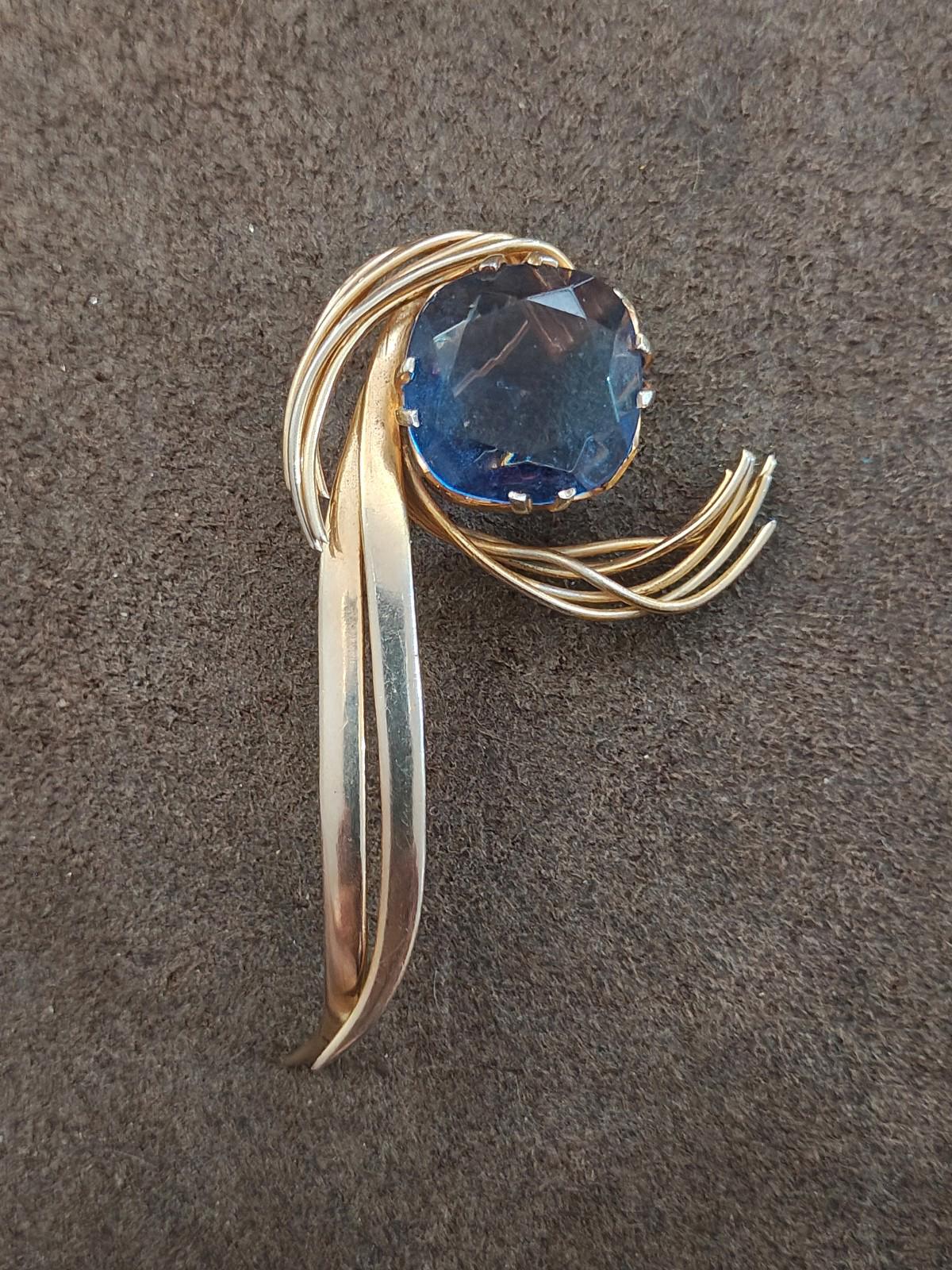 Gold-tone abstract brooch pin with large blue gemstone and looping wire accents