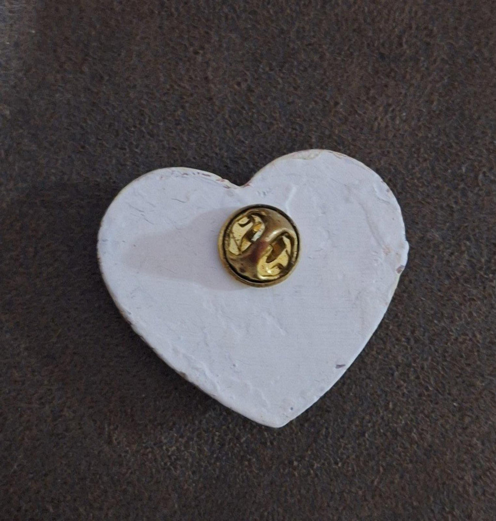 Heart-shaped resin pin with crackled white front and gold-tone metal pin backing