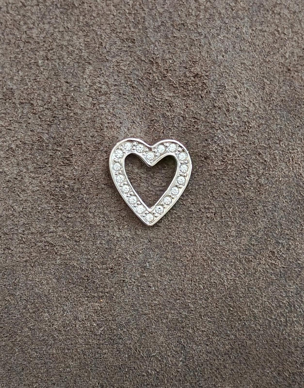 Small silver-tone open heart rhinestone pin on textured background