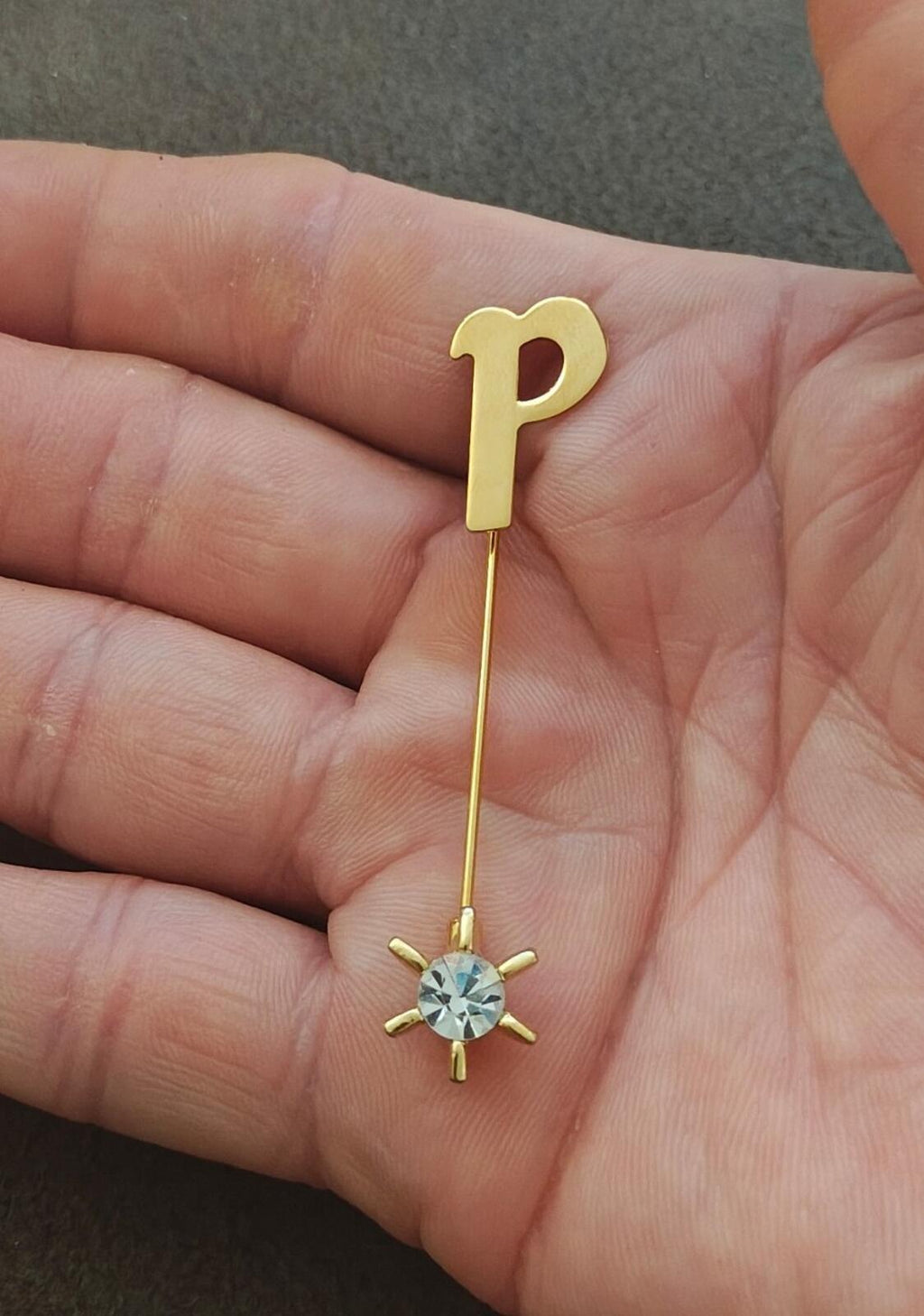 Gold tone initial P stick pin with round blue crystal charm on a long bar.