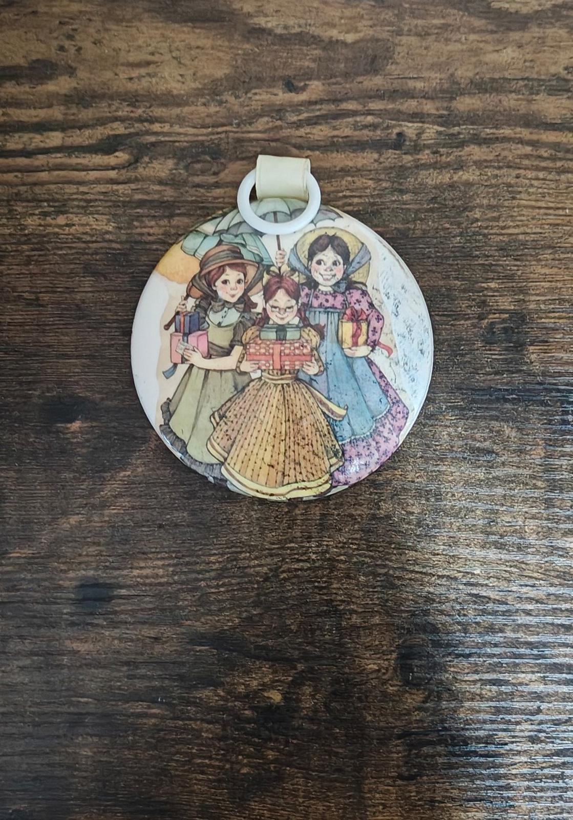 Round hanging ornament with illustrated girls in prairie dresses, cream top loop