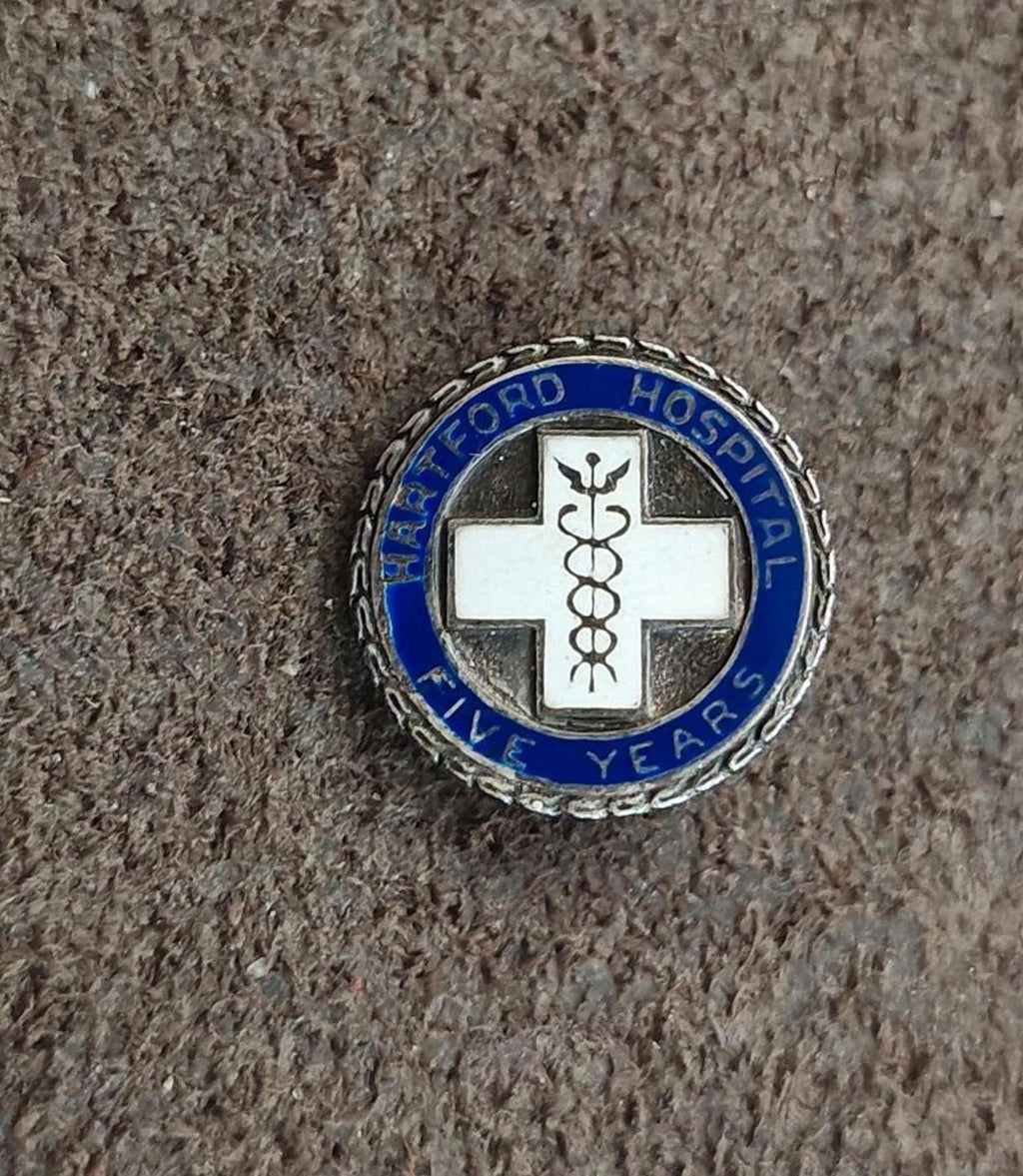 Hospital service enamel pin, round design with blue lettering ring and white cross emblem