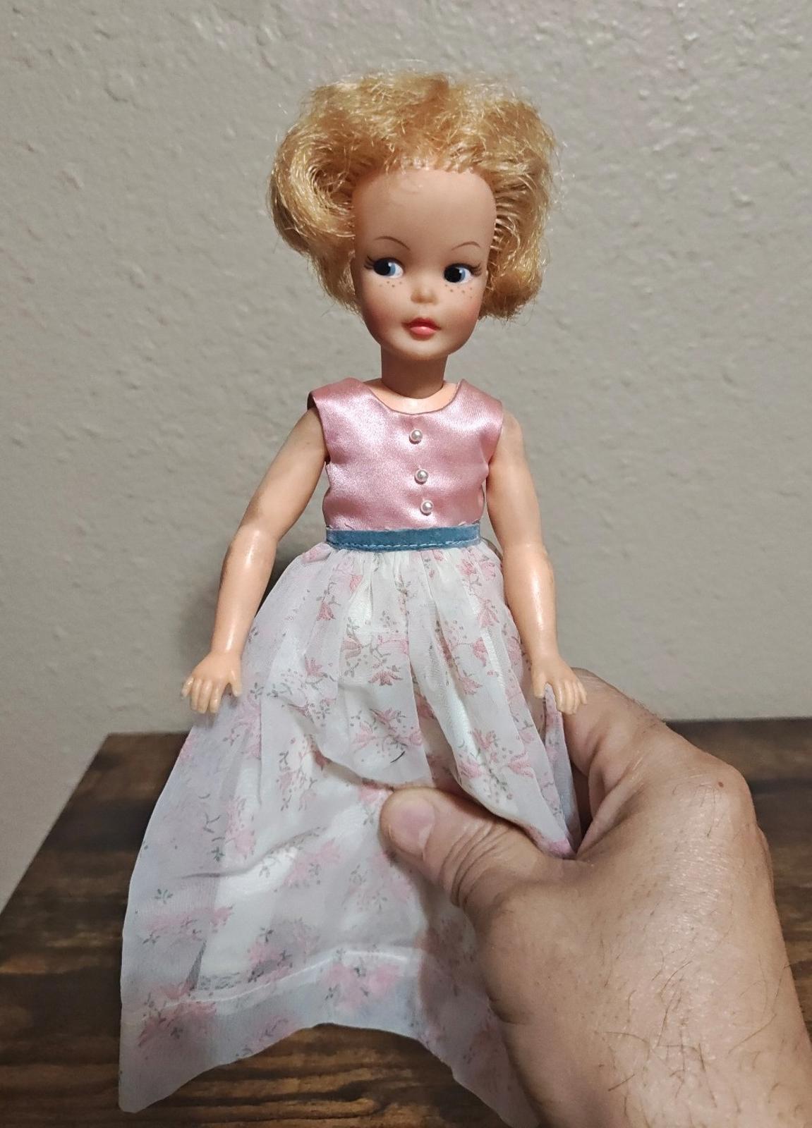 Vintage pepper doll with blonde yarn hair, pink satin dress, floral skirt, blue belt
