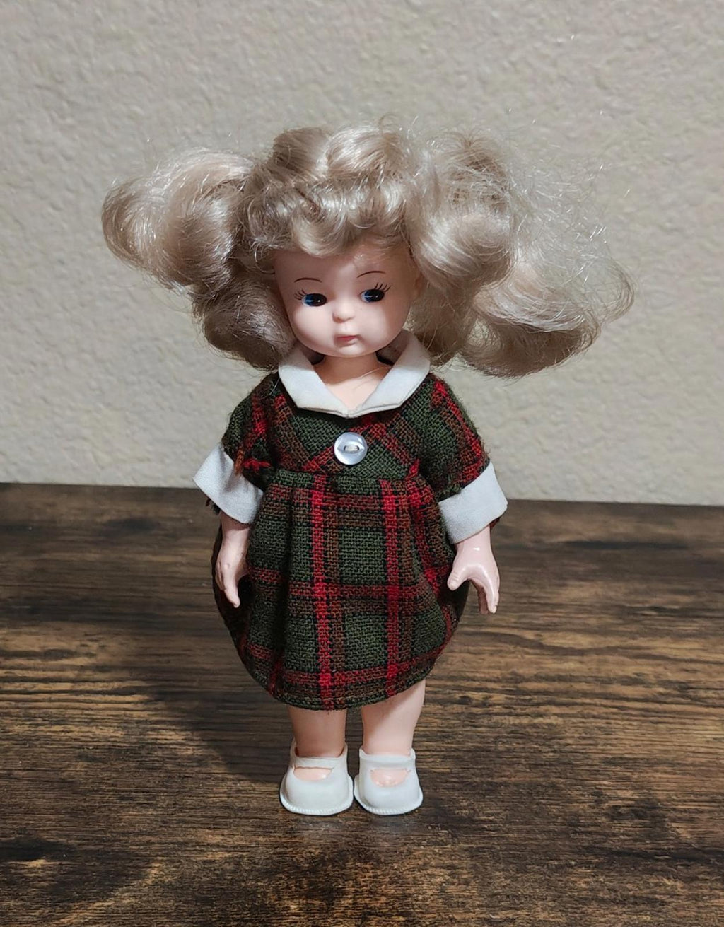 Vintage doll standing front view, curly light-brown hair, green plaid dress, white shoes