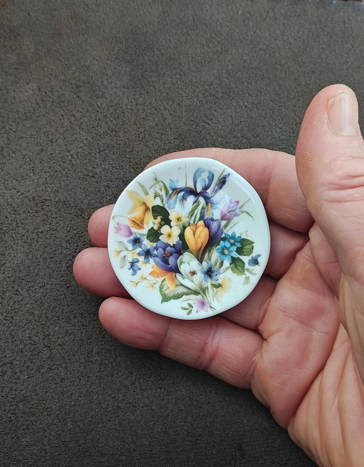 Tiny round floral decorative plate with blue and yellow blooms, green leaves, and pink details