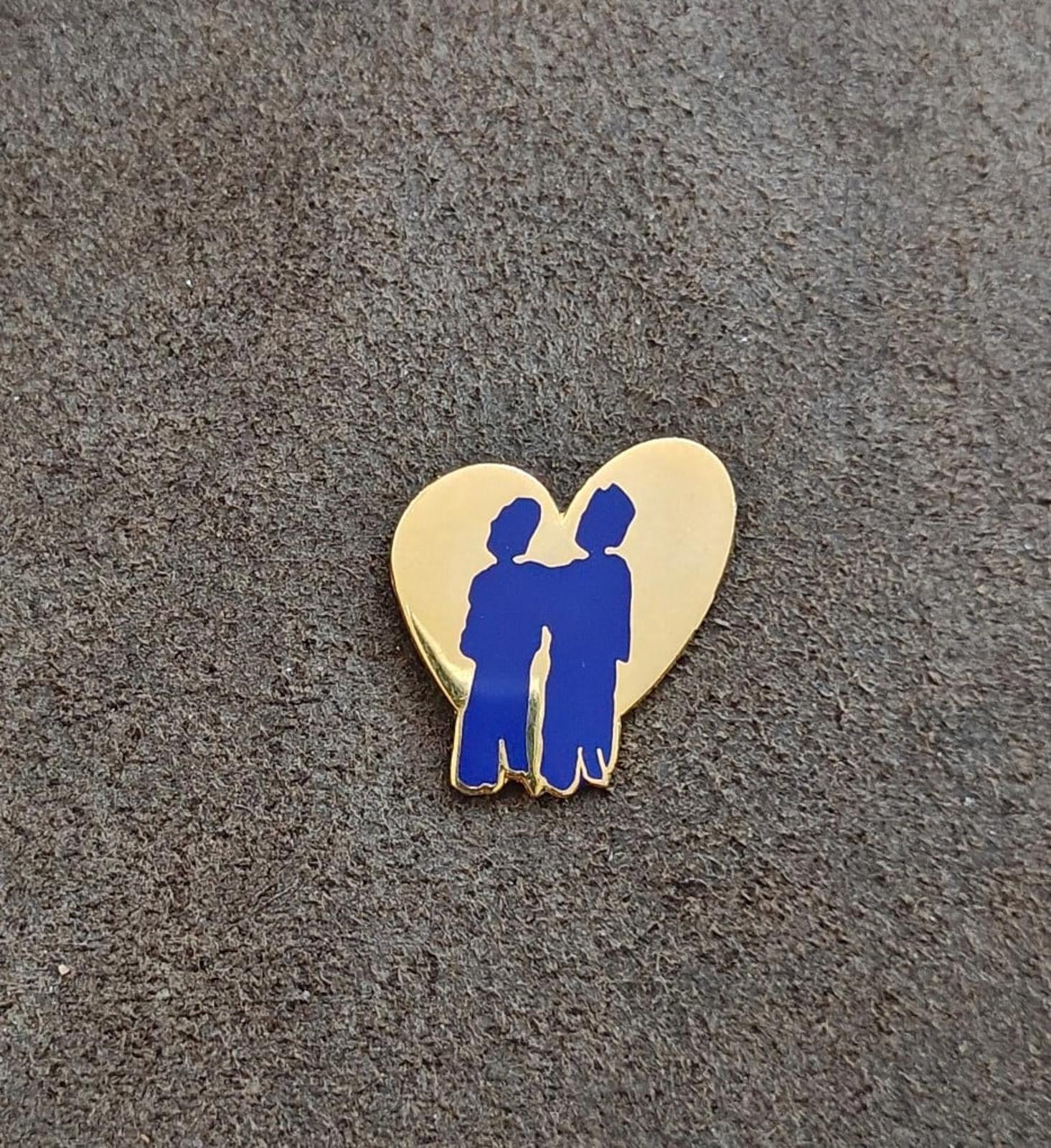 Small heart-shaped enamel pin with blue two-friends silhouettes