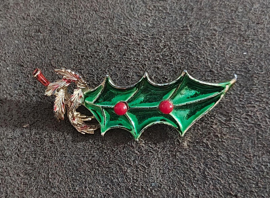 Green enamel holly brooch with gold tone twig, pointed leaves, and red berries.