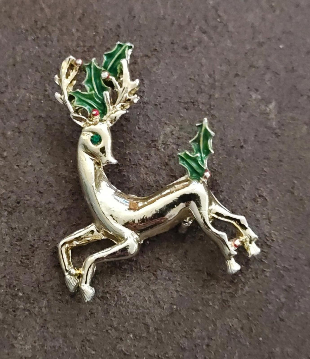 Gold-tone reindeer brooch with green enamel holly, angled side view