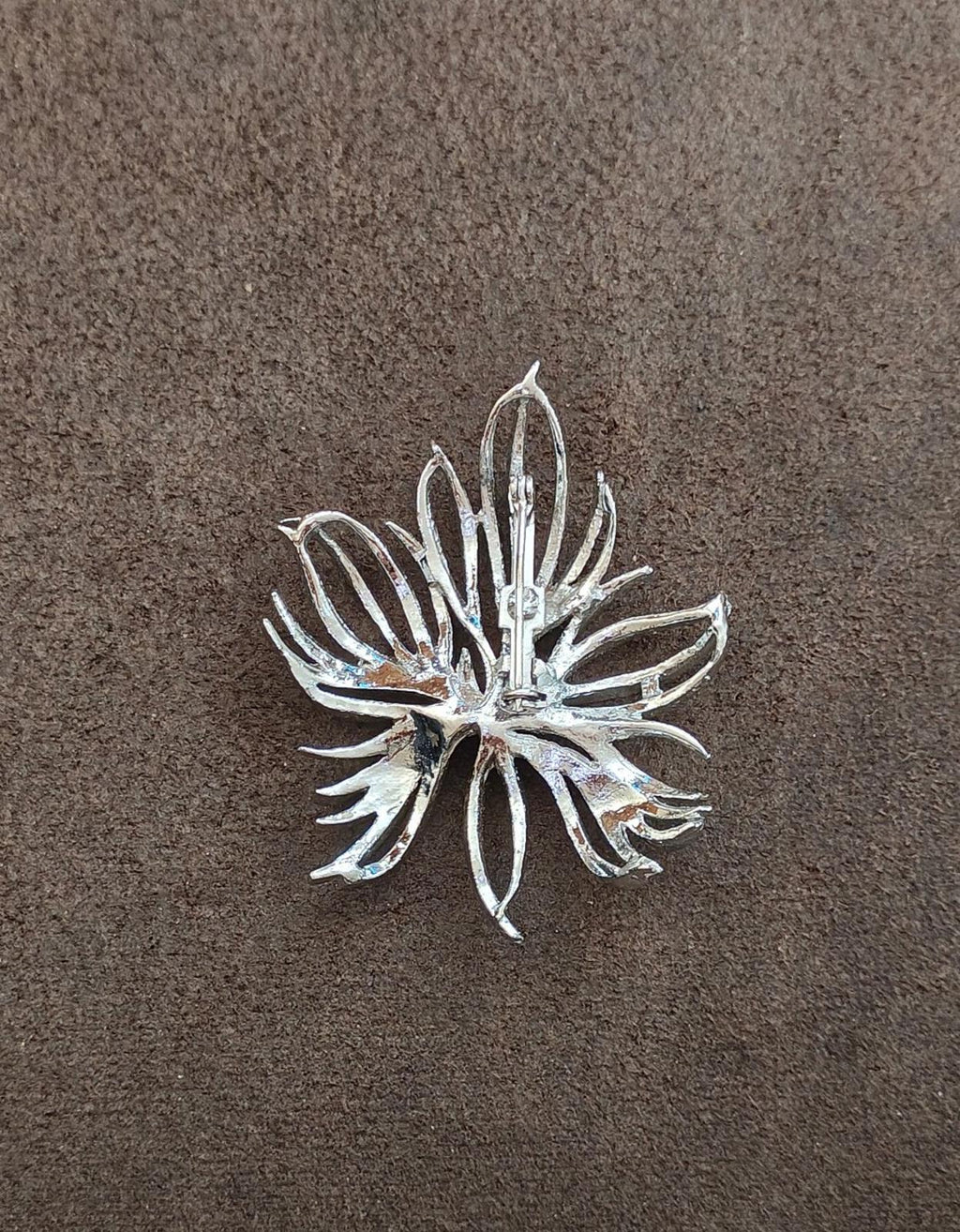 Silver tone leaf pin brooch with frosted texture, top view on flat surface