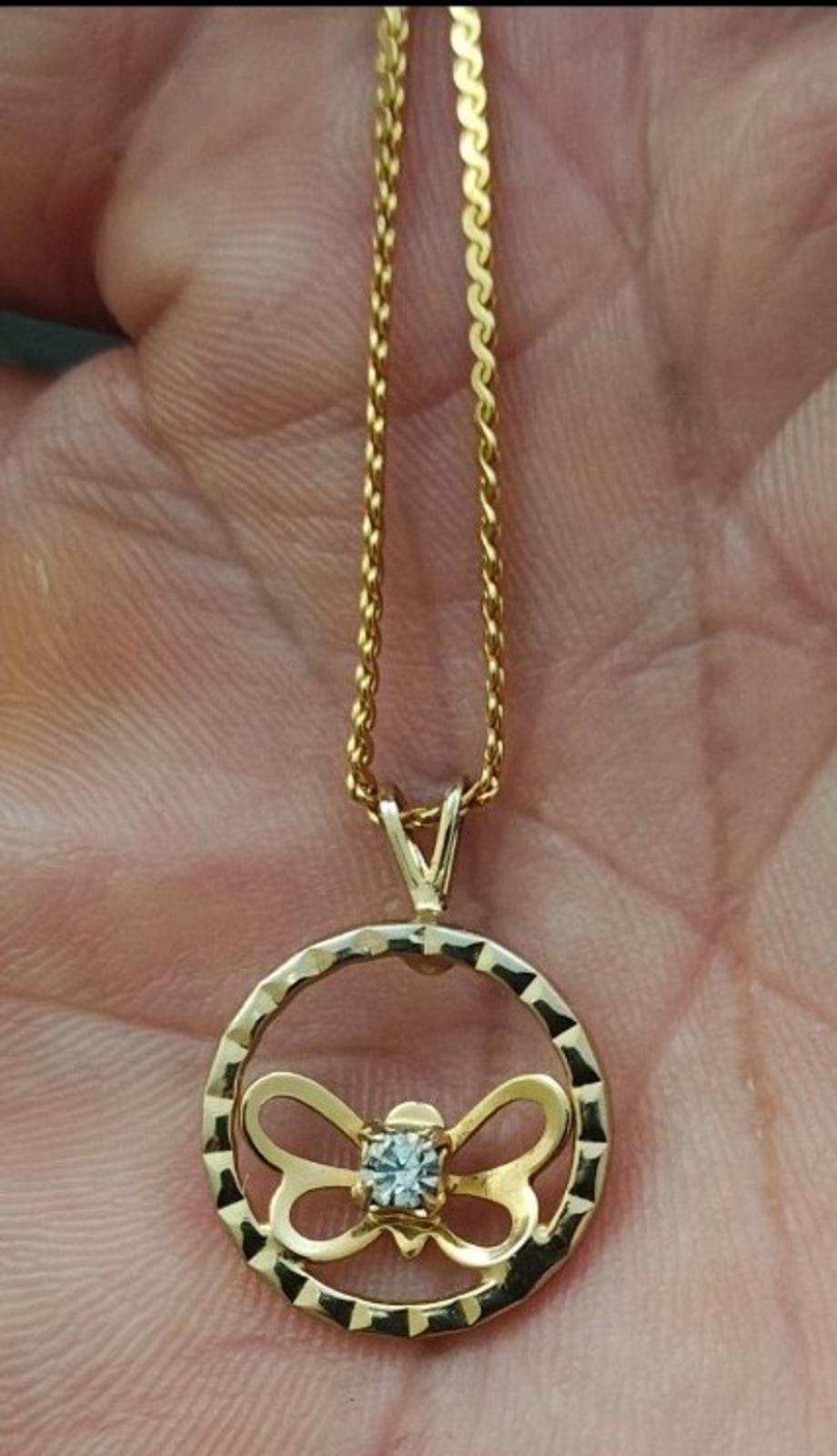 Gold-tone necklace with open circle round pendant, bow-like butterfly detail, clear rhinestone