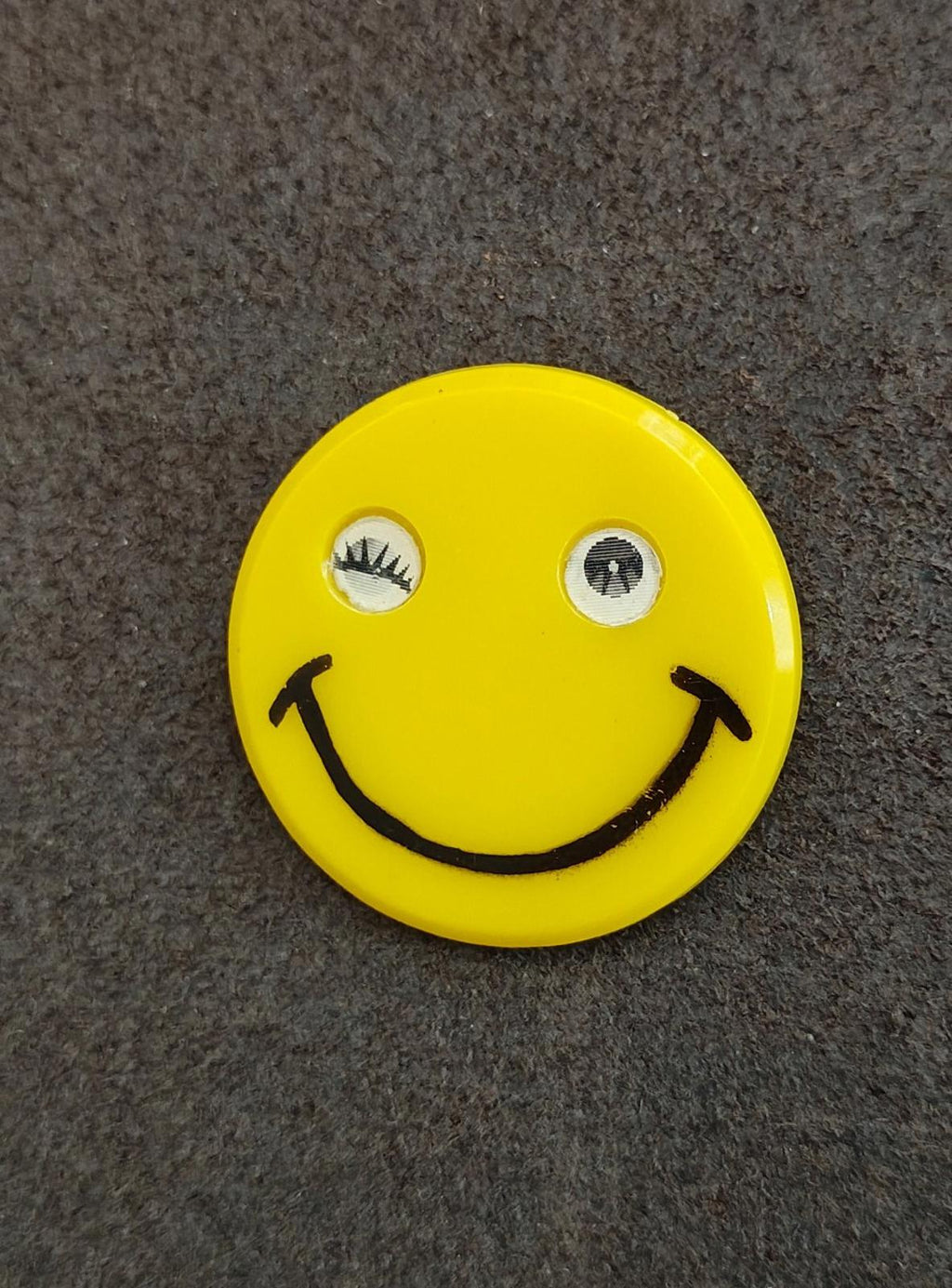 Yellow round smiley face pin with mirrored eyes and black smiling mouth