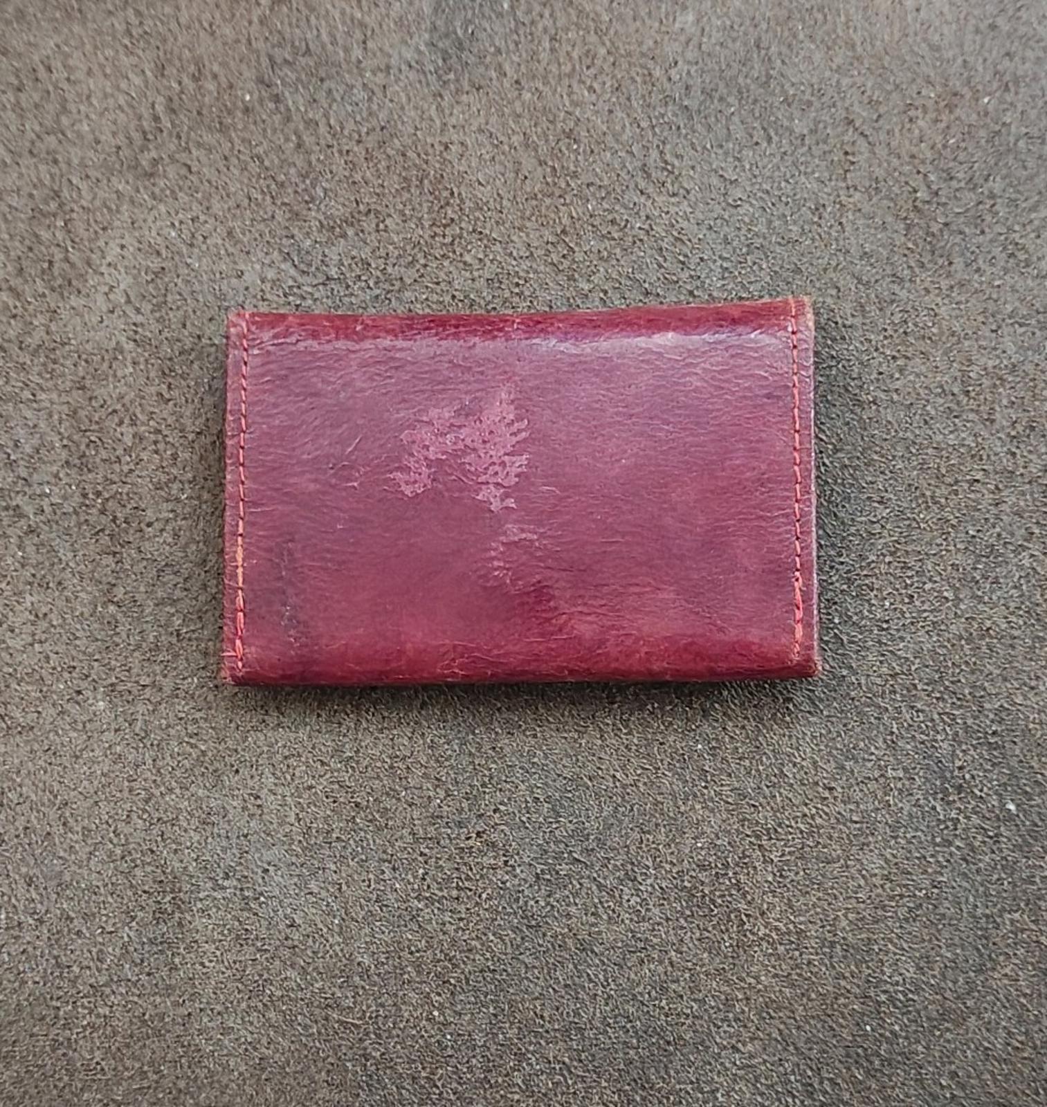 Rectangular burgundy coin purse wallet with distressed leather texture and stitched edges.