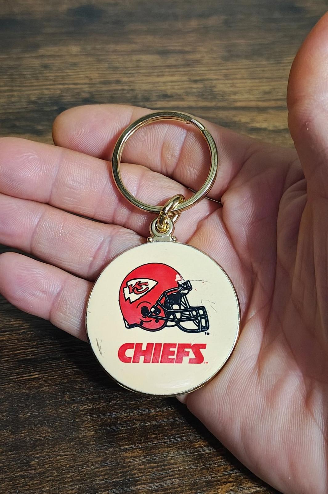 Kansas City Chiefs keychain with gold ring and round white enamel face showing red helmet