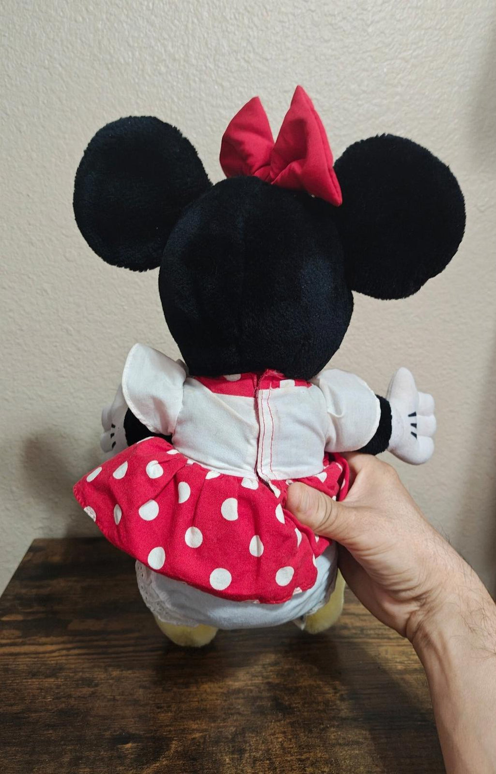 Minnie Mouse plush back view with black ears, red polka-dot skirt, white sleeves