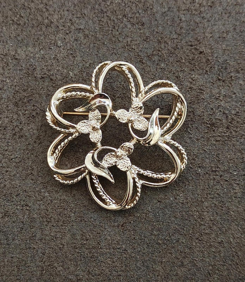 Gold-tone floral brooch with curled petal loops and textured center decorations