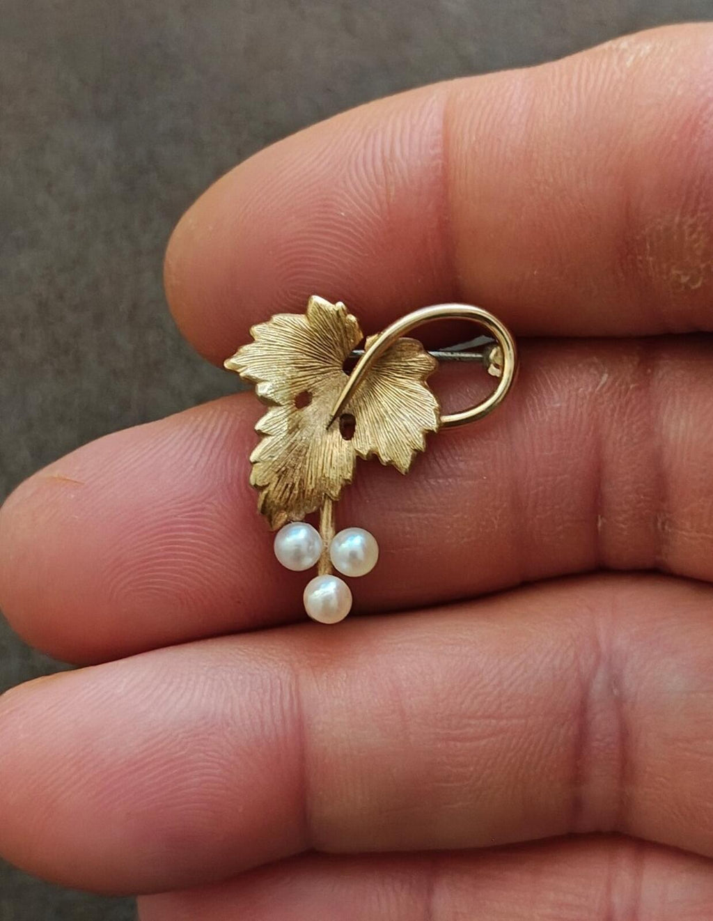 Gold grape-vine brooch with two cultured pearls hanging below leaf cluster