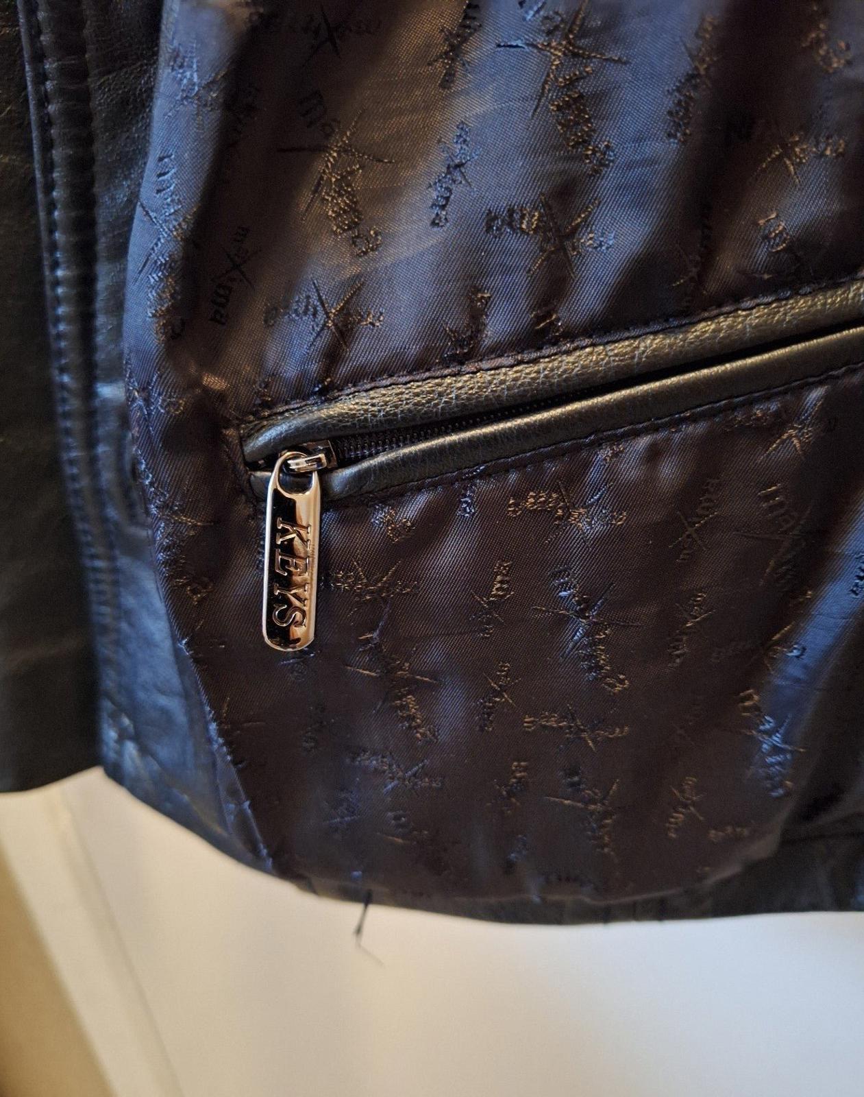 Close-up of front pocket zipper on women's black leather jacket