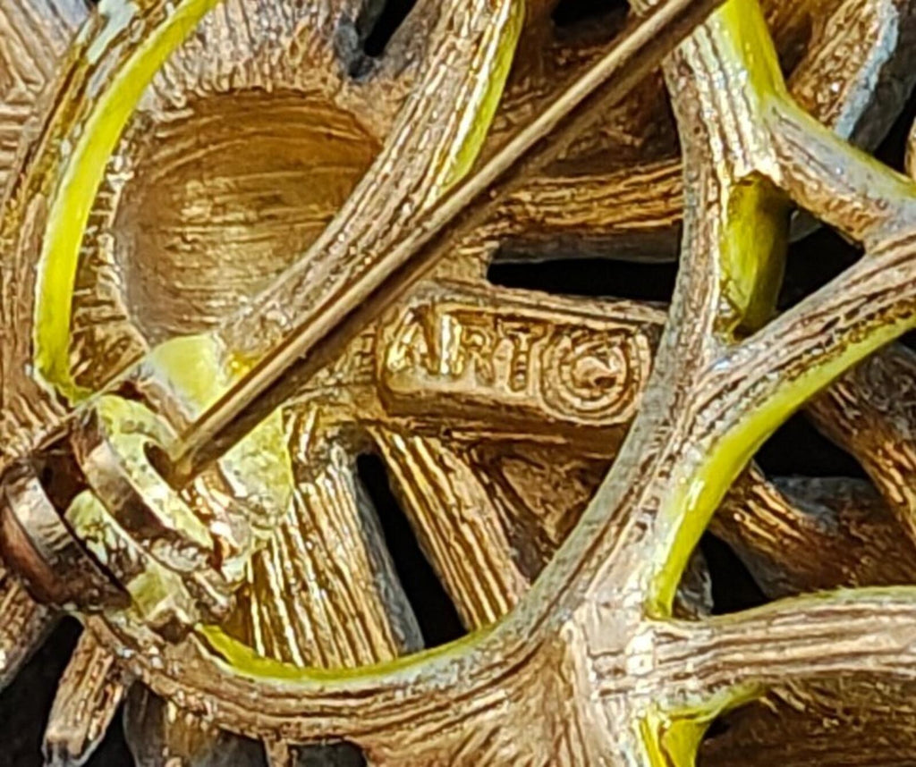 Close-up of engraved signature on gold-tone daisy brooch back plate