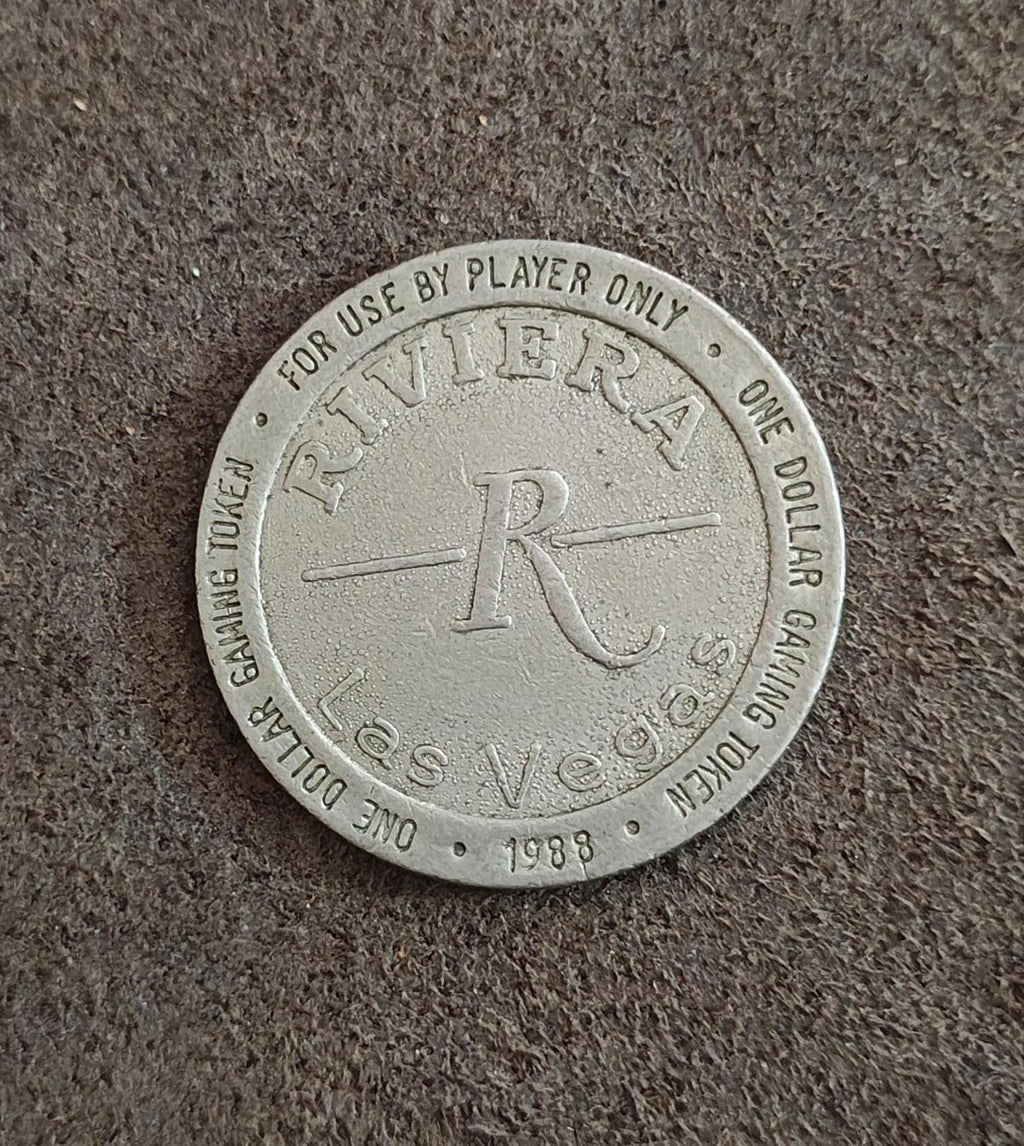 Silver one-dollar gaming token with Riviera logo and 1988 date on rim