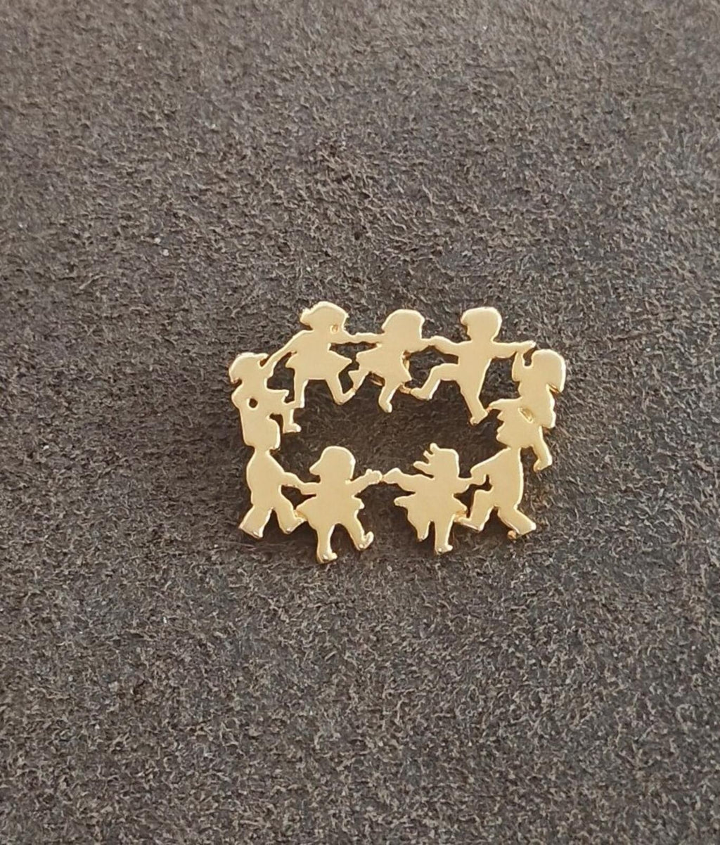 Gold children silhouette pin with Ring Around the Rosie wreath design, flat lay view