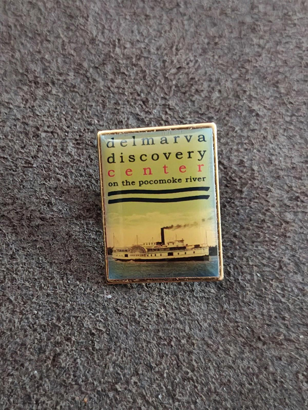 Gold Delmarva Discovery Center pin front view with ship graphic and text
