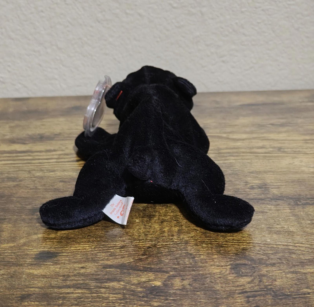 Black plush bear beanbag showing back side with small fabric tag at bottom