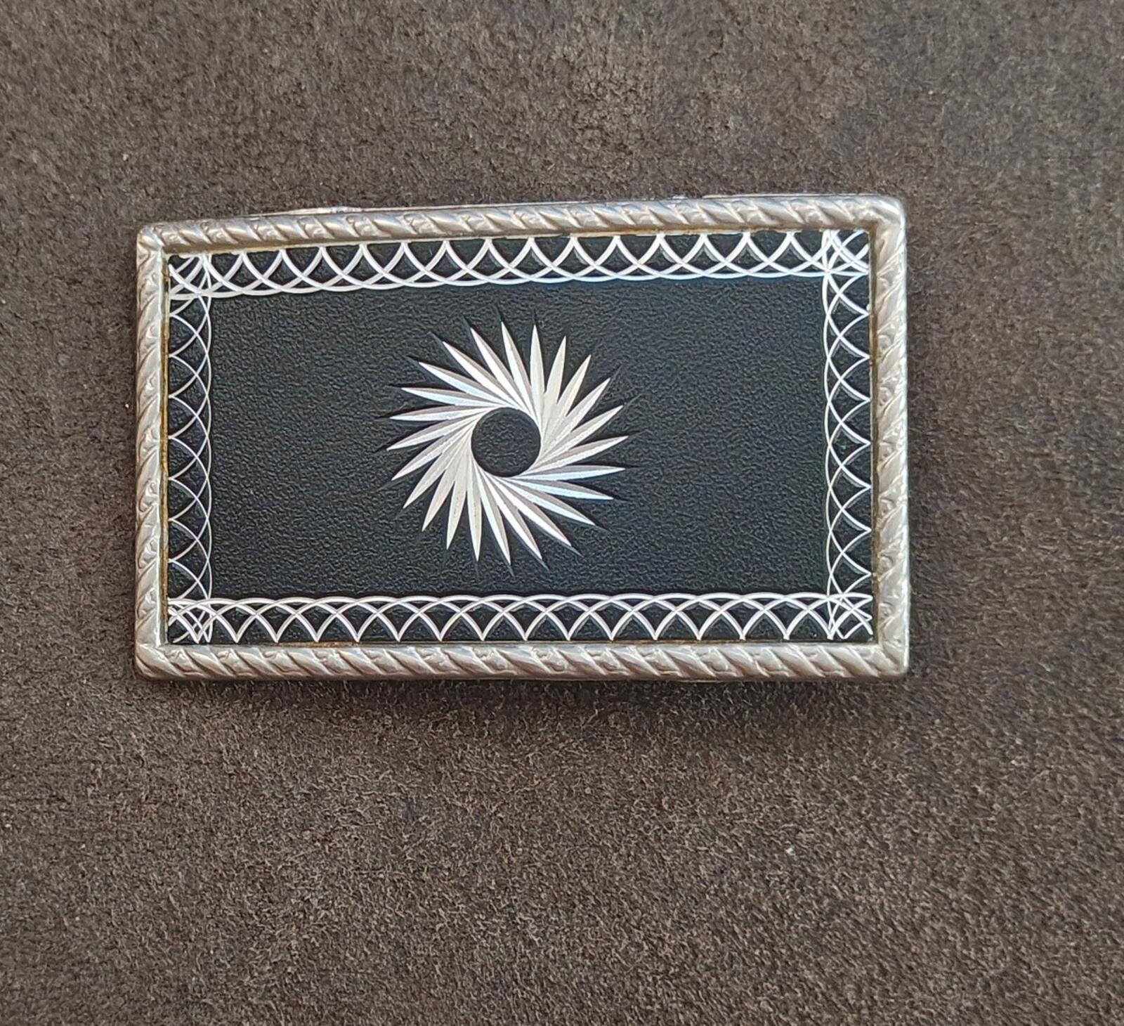 Western belt buckle with silver starburst design and ornate border trim